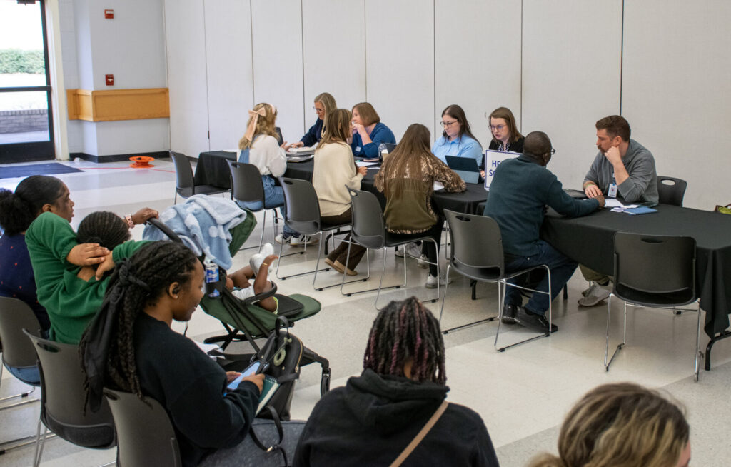 Photo of NCC team members helping students in auditorium.