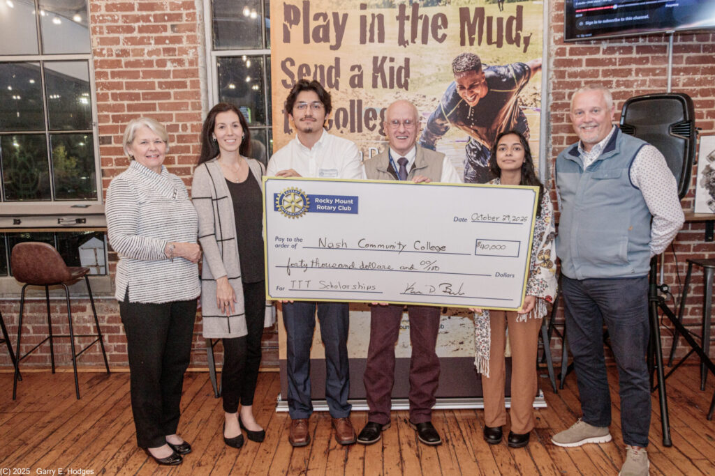 Photo of Dr. Lew Hunnicutt (middle) with two NCC students on right and left of him, accepting the $40,000 check from Tackle the Tar.