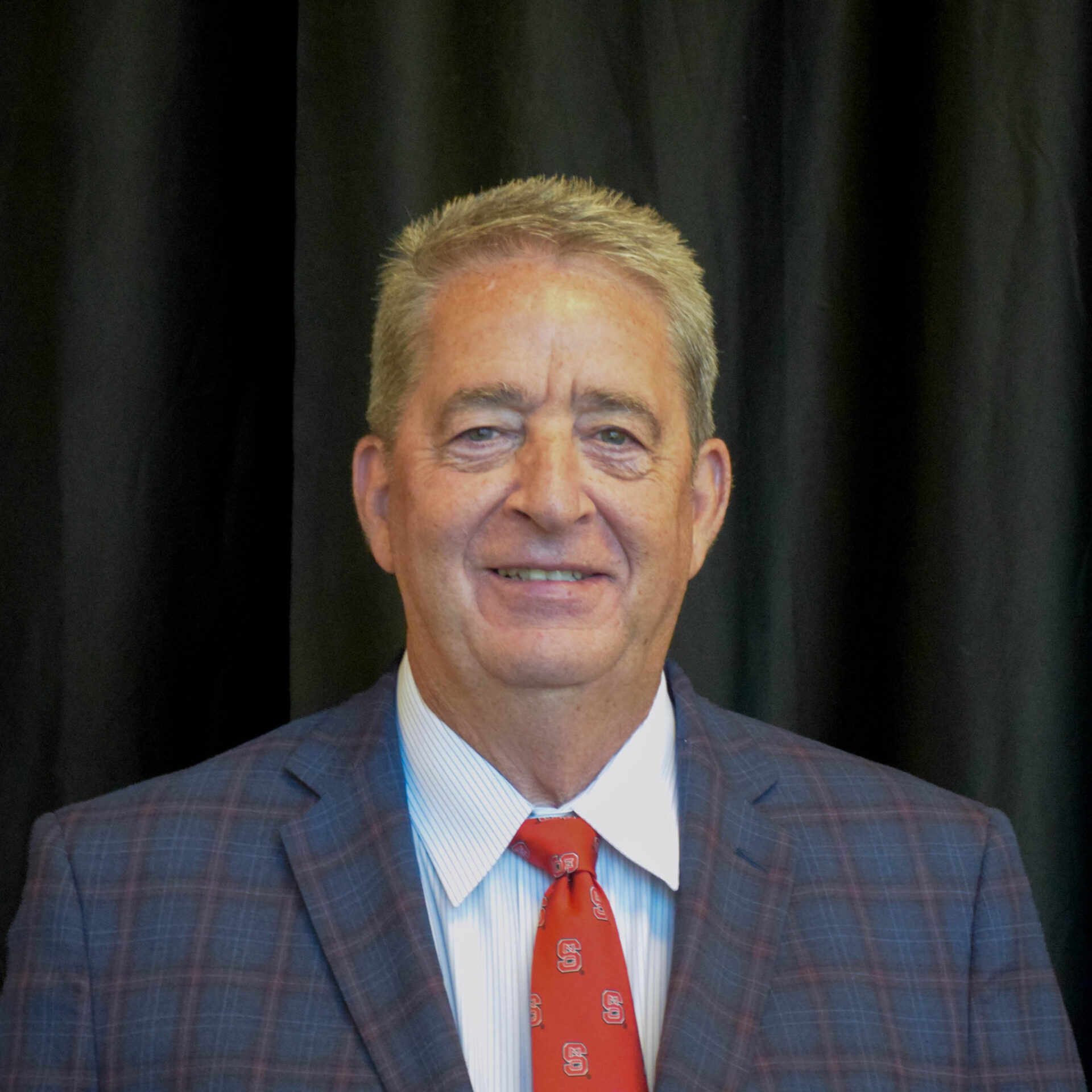 Headshot of a man in front of a black curtain